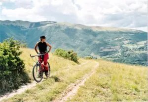 Image of woman looking back over her shoulder on a mountain bike on a track on a hillside to illustrate post