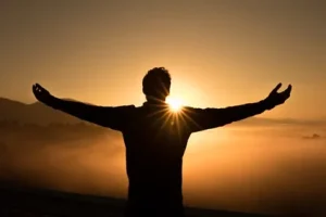 Image of a person with his arms outstretched at sunset to illustrate post