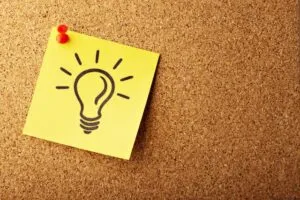 Image of post-it note with light-bulb image on it, pinned to a cork noticeboard to illustrate post