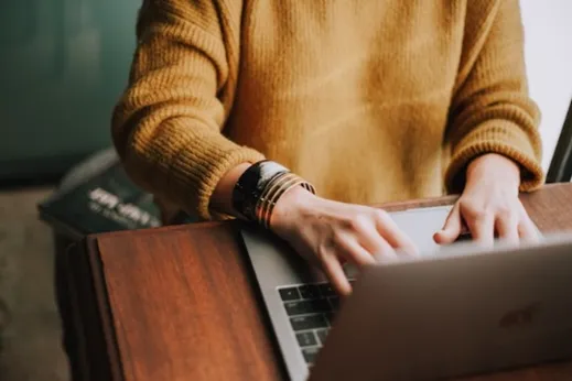 Image of person wearing yellow jumper and bangles on right wrist, typing on laptop keyboard, to illustrate post