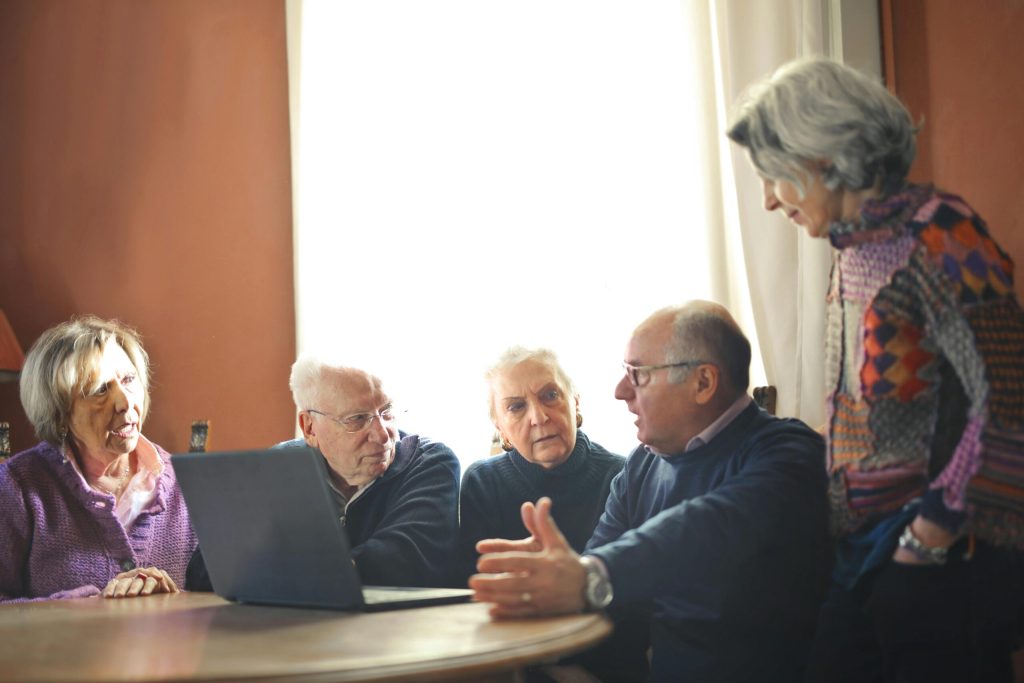 Image of a group of old people looking at a computer and talking together, used to illustrate post.