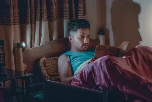 Image of a man reading a book in bed to illustrate post