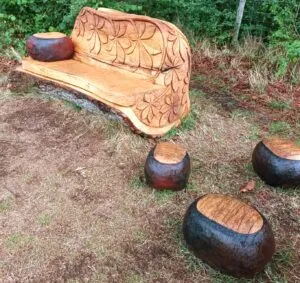 Photograph of Carved wooden bench made from a tree trunk, with giant chestnuts scattered around, and one on the bench, to illustrate post