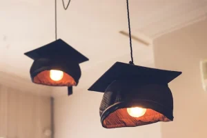 Image of a pair of graduation caps hanging from the ceiling as light shades to illustrate post