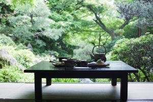 Image of tea accesories on a table, with a garden in the background, used to illustrate the post
